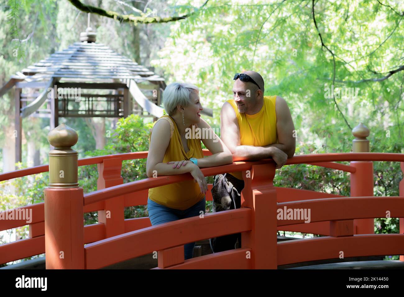 Young couple laughing while standing in the park on bridge Stock Photo
