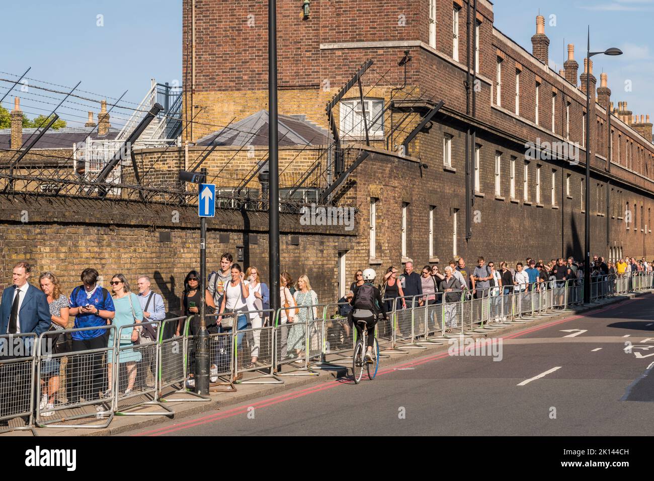 A long queue of visitors passes behind Buckingham Palace along Grosvenor Place, waiting to enter Green Park in order to lay flowers there in memory of the late Queen Elizabeth II, or to see the floral tributes left there by thousands of other people Stock Photo