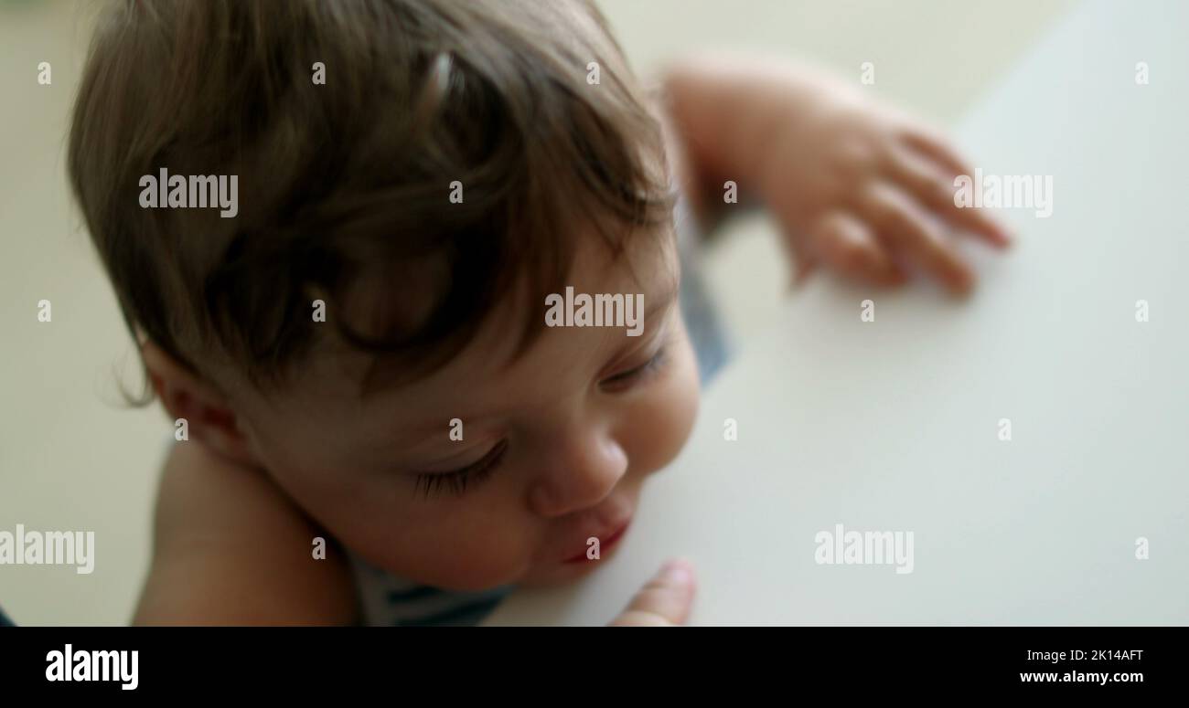 Cute baby toddler learning to stand holding into parent leg, infant one ...