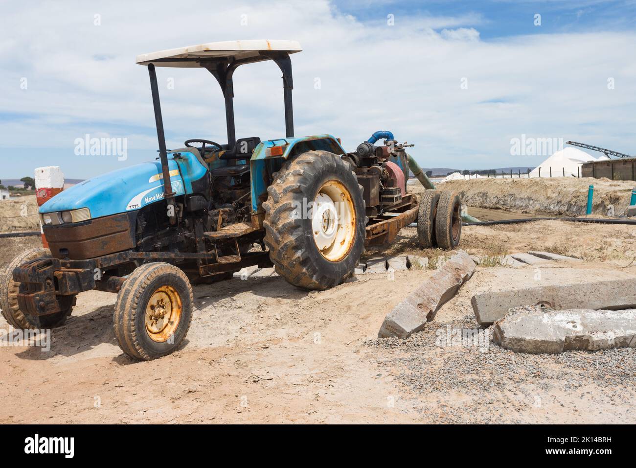 tractor attached to machinery or equipment working with pipes outdoors at a salt factory or salt pan Stock Photo