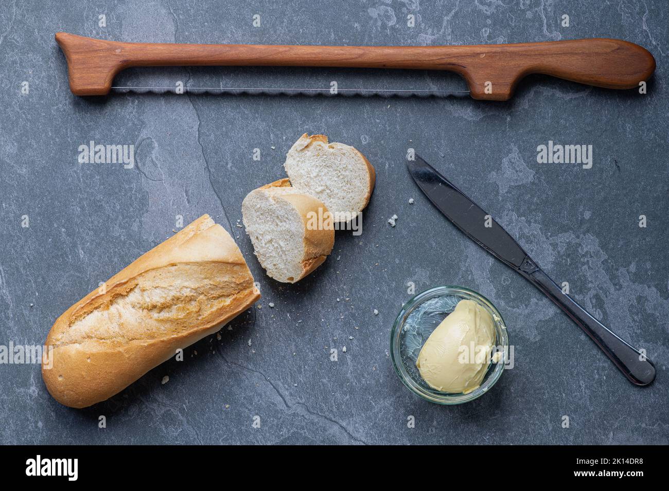 Baguette on a kitchen worktop counter topwith a fiddle bow knife. Stock Photo