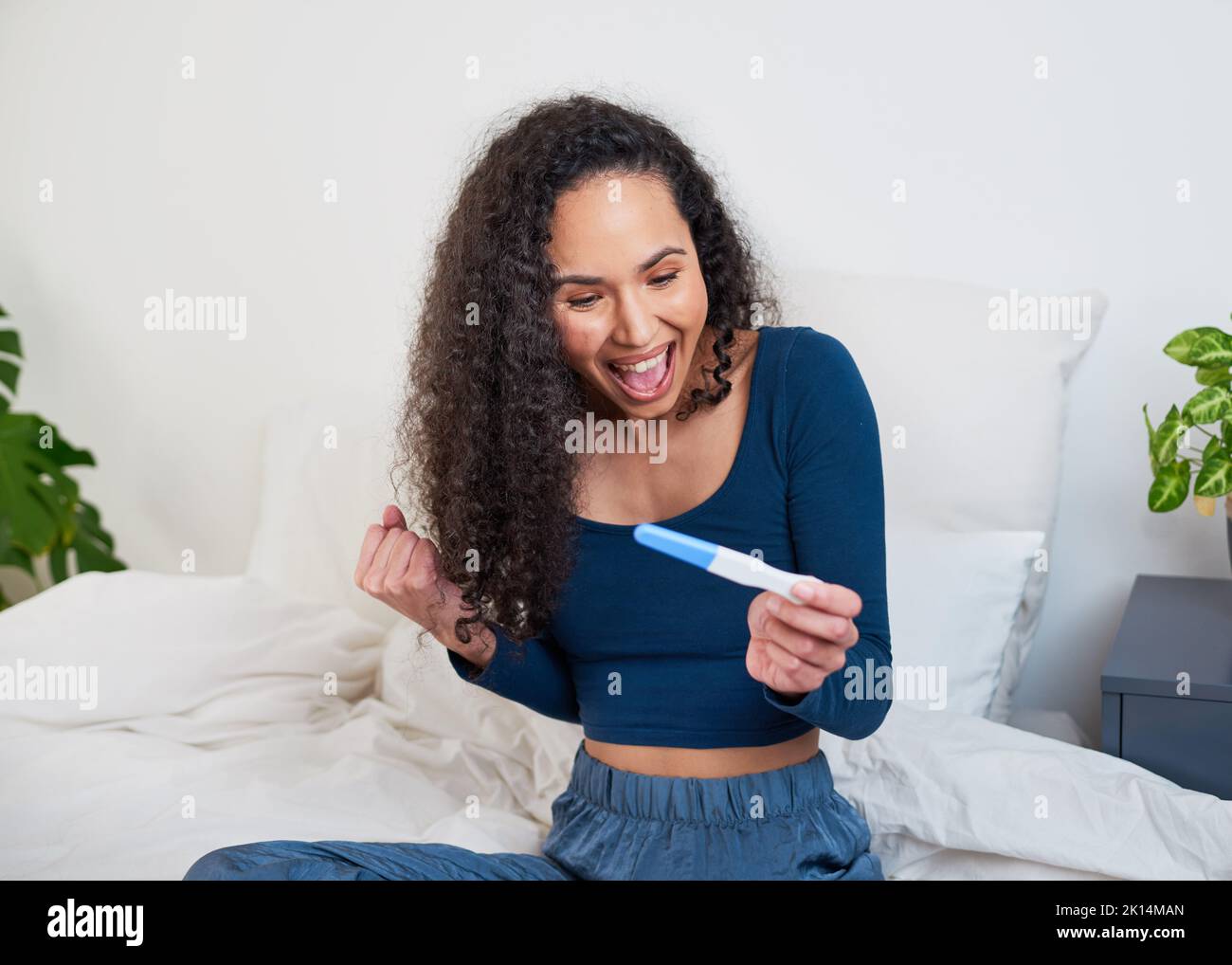 A young multi-ethnic woman is ecstatic and happy to see pregnancy test results Stock Photo