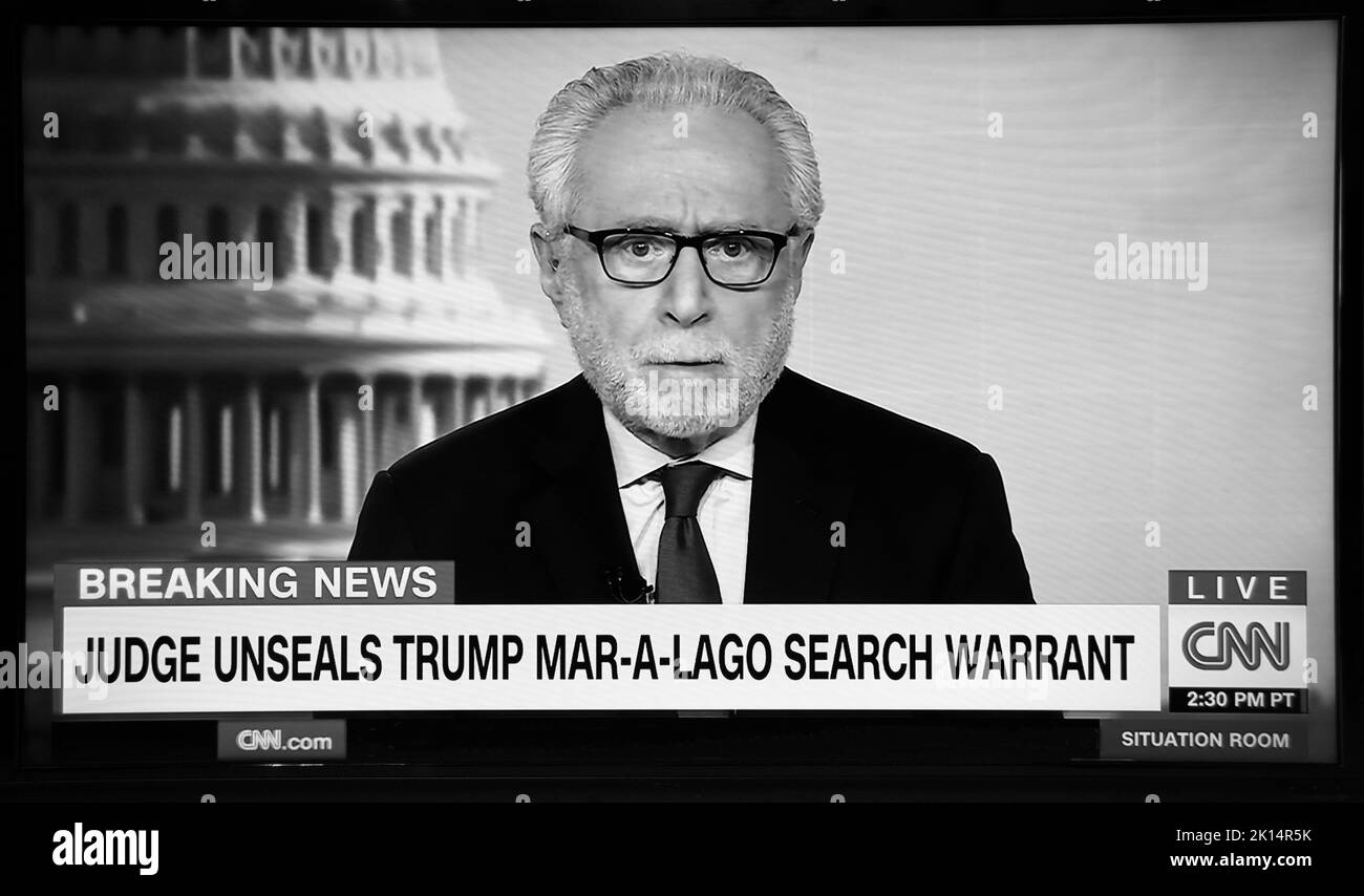 A TV screenshot of CNN news anchor Wolf Blitzer reporting developments in the FBI search of Donald Trump's home in Florida. Stock Photo