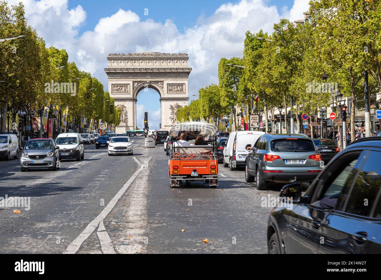 Famous landmark The Arc de Triomphe at the western end of the Champs-Élysées. Red TukTuk and cars near the triumphal arch, Paris, France Stock Photo
