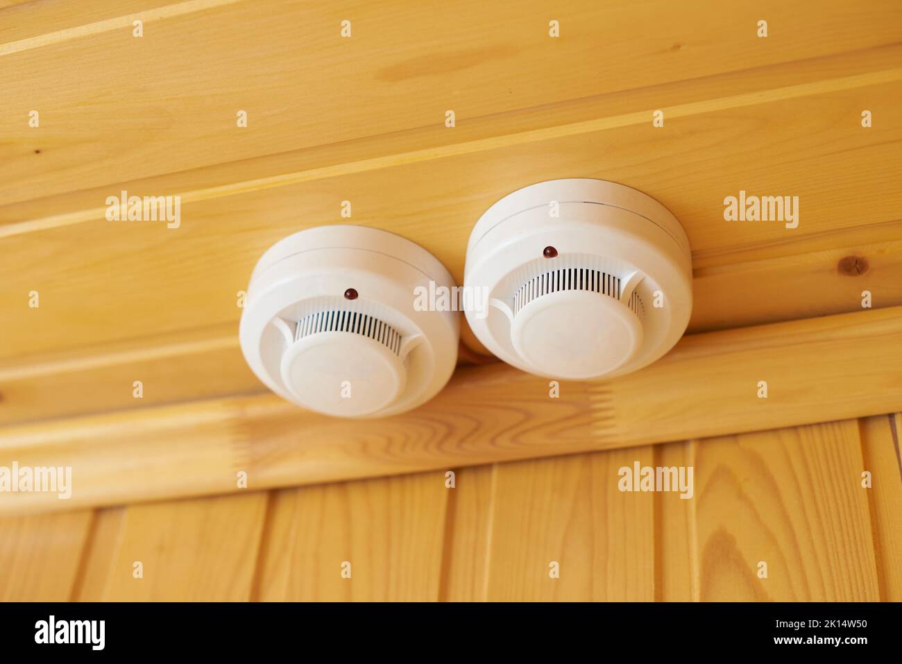 Smoke detector of fire alarm system on a wooden wall. Stock Photo