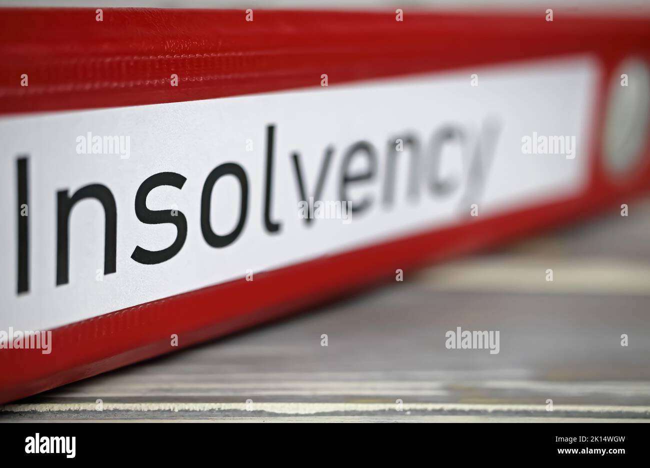 Closeup of isolated red file folder with english word insolvency on wood table (selective focus on center of letter S) Stock Photo