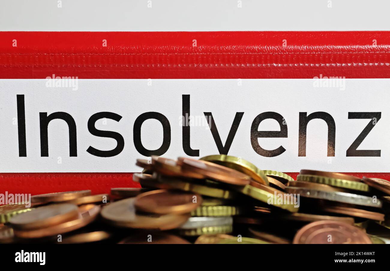 Closeup of isolated red file folder with german word Insolvenz (engl. translation: insolvency), pile dept mountain coins Stock Photo