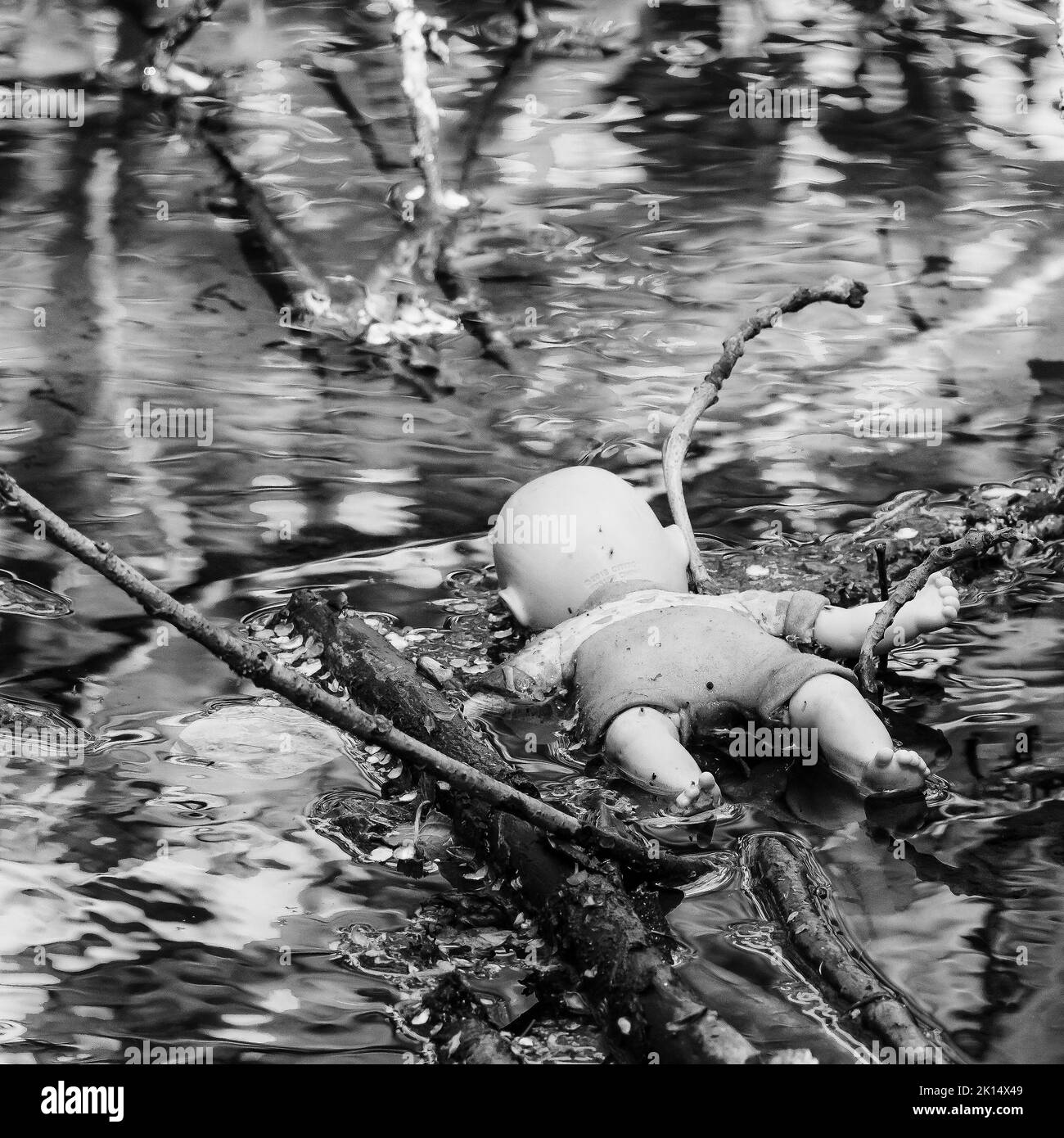 Child's doll facing down in a canal - Spooky, Horror, Crime scene. Stock Photo