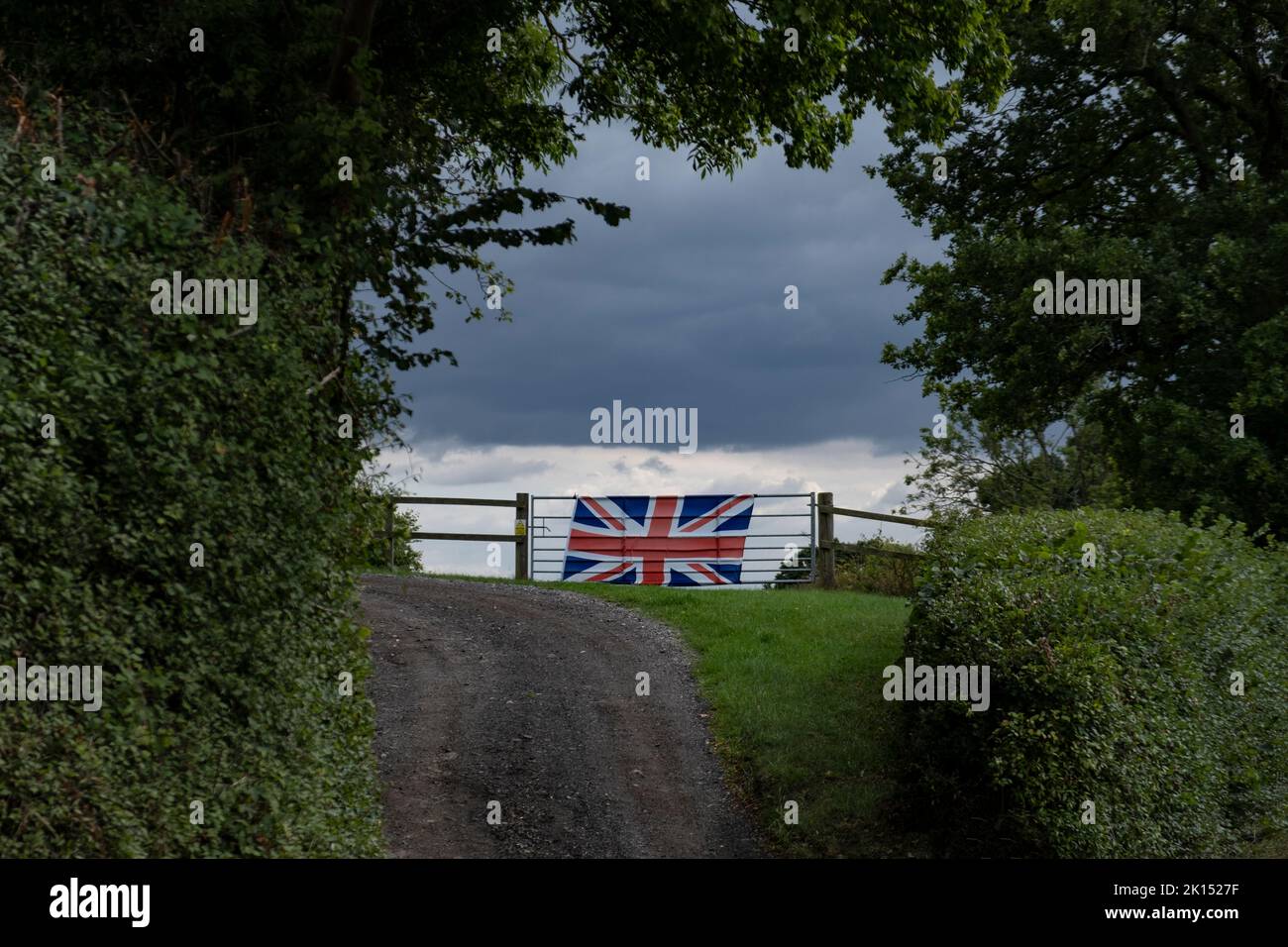 A Union Jack flag hangs in tribute from a farm gate in the Worcestershire countryside, UK. Stock Photo