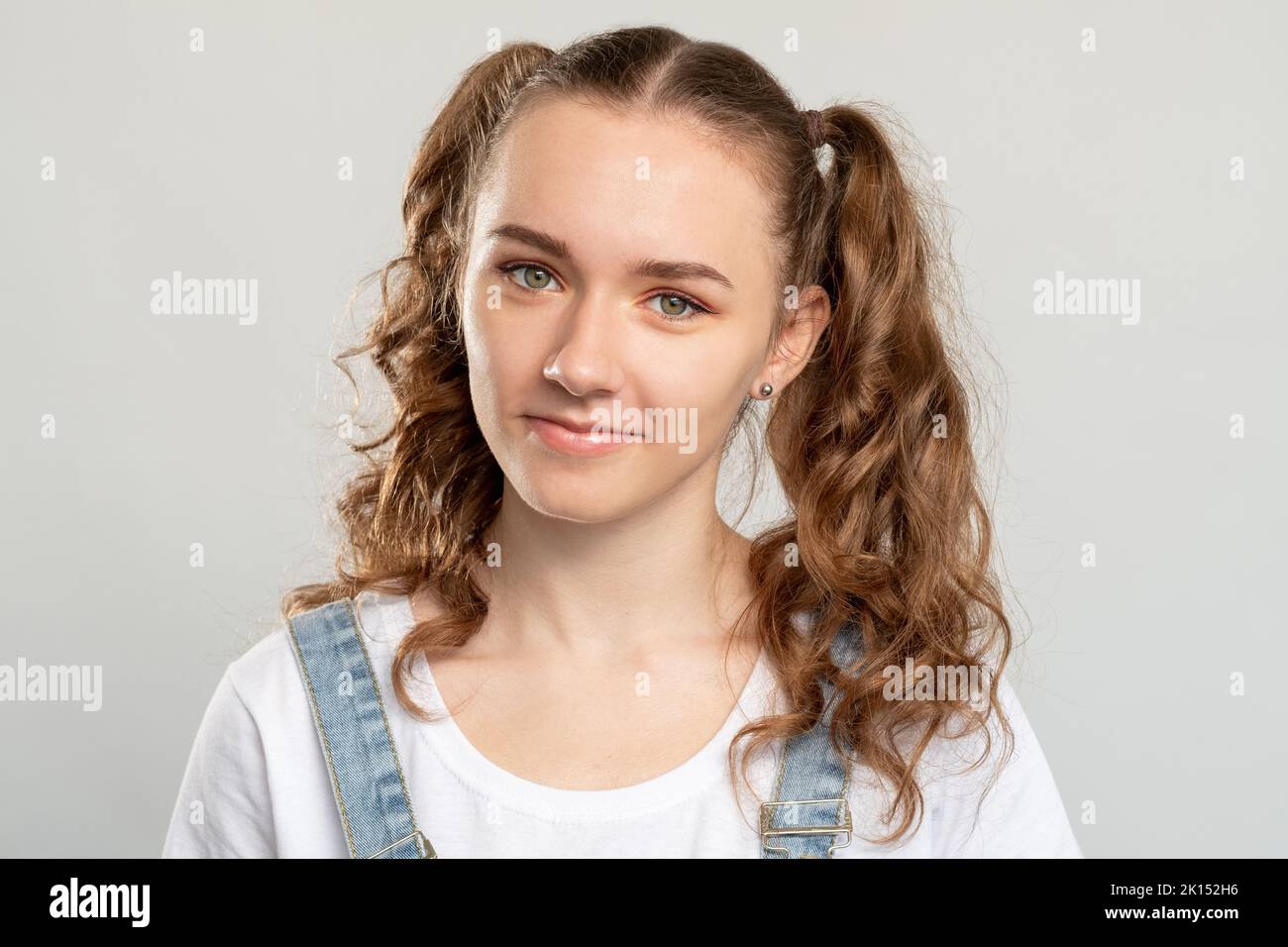 Teen girl portrait. Youth lifestyle. Happy woman with 2 ponytails cute hairstyle smiling isolated on neutral background. Tenderness beauty. Stock Photo