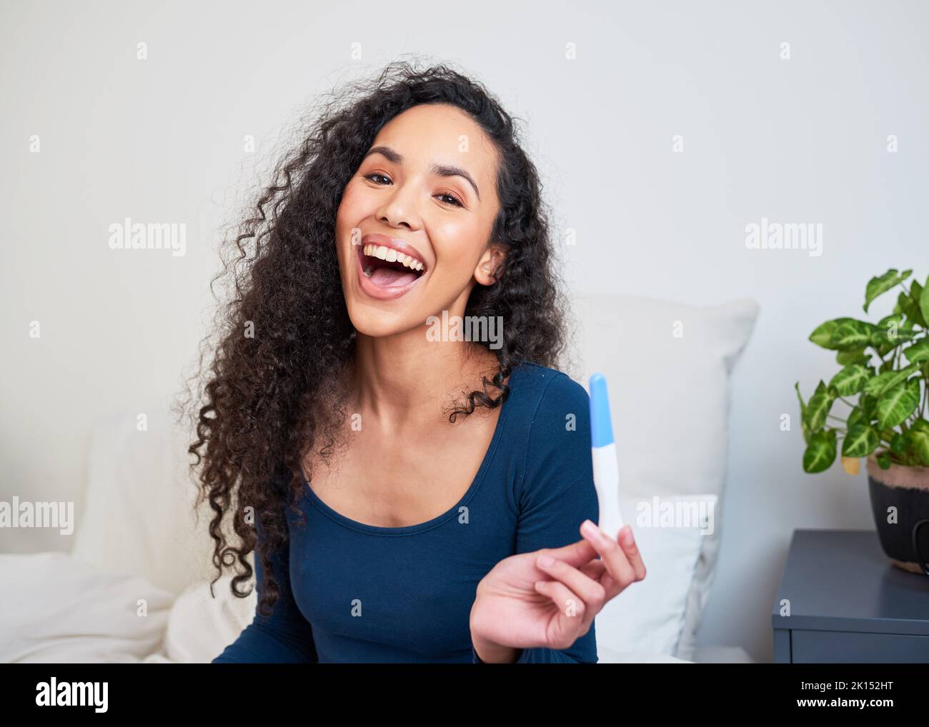 A young multi-ethnic woman is ecstatic and happy to see pregnancy test results Stock Photo