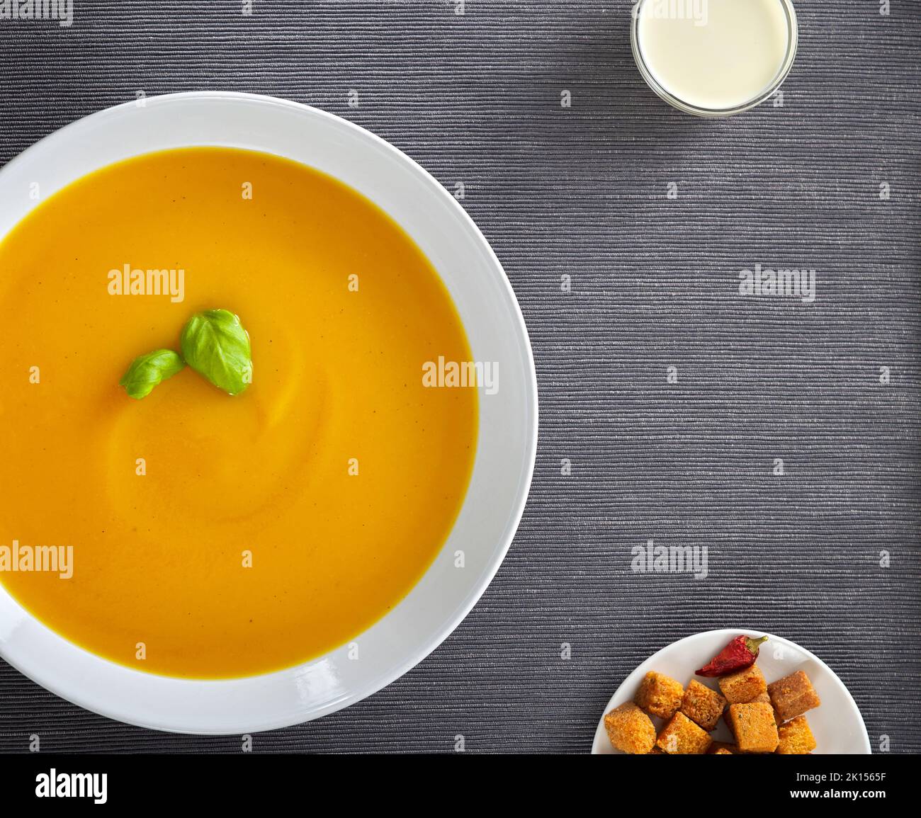 Pumpkin traditional soup with croutons and sour cream. Gray rug background. Copy space. Top view. Stock Photo