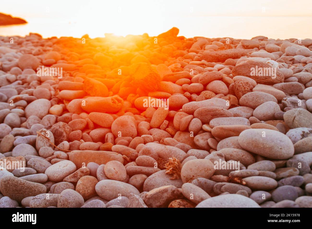 Stones and pebbles on Trefor beach, North Wales with a orange red sunset Stock Photo