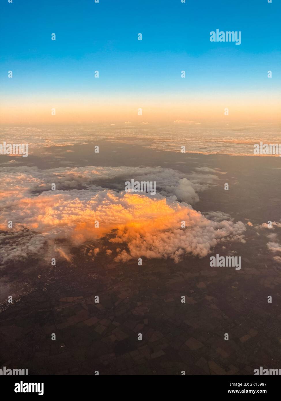 Amazing view of white fluffy clouds in sky from a plane at sunset Stock Photo