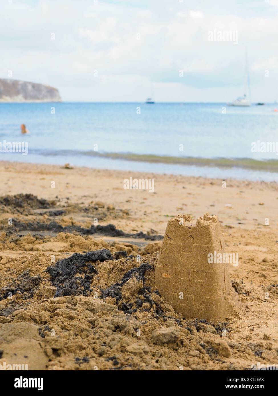 Close-up of a sandcastle on a beach with a blurred background of sea and cliffs Stock Photo