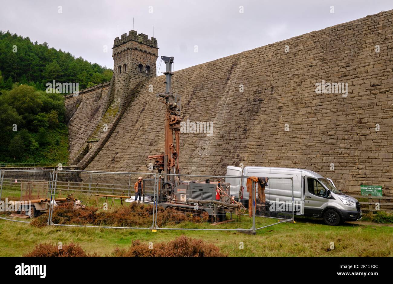 Workmen with industrial machinery at the base of the huge dam wall by Derwent reservoir. Stock Photo