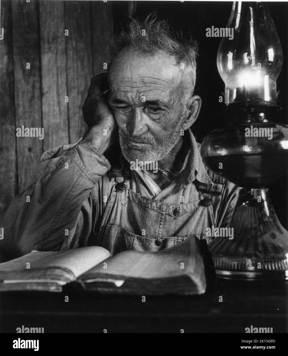 A rural farmer reads his Bible by a kerosene lamp near Maxton, NC; 1959. Stock Photo