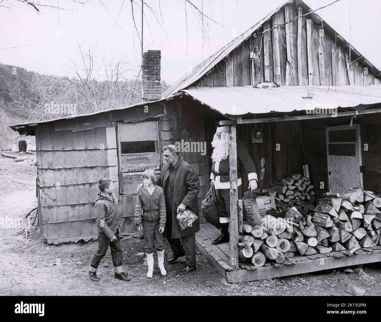 Santa Claus brings presents to children in Appalachia, thanks to the Parson of the Hills; 1965. The charity was set up to provide gifts to the children of the Appalachias. Here, the Parson and Santa give out gifts to two kids outside their home. Stock Photo