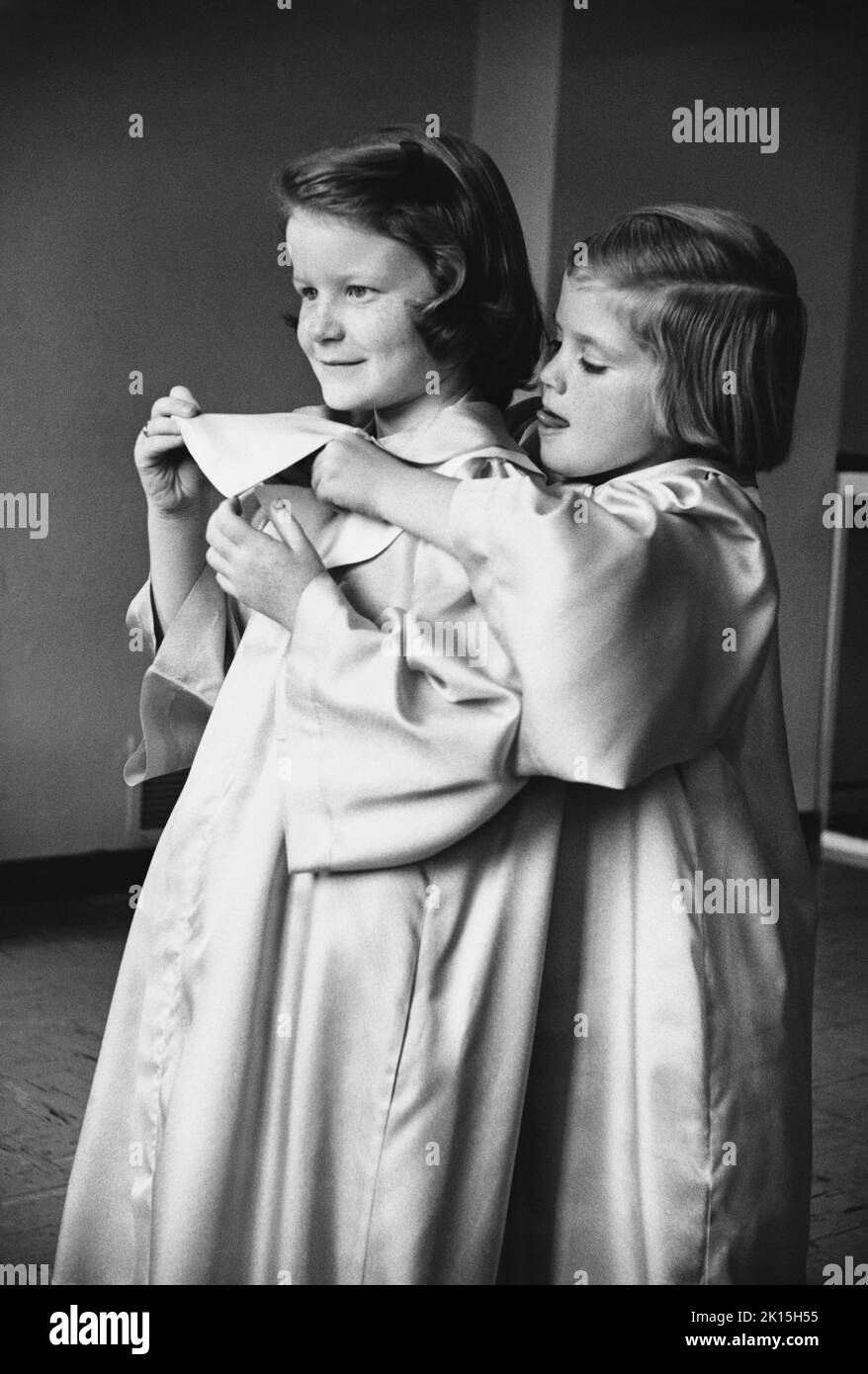 Church choir children, Tusla, Oklahoma. One girl helps another get her robe on straight. Stock Photo