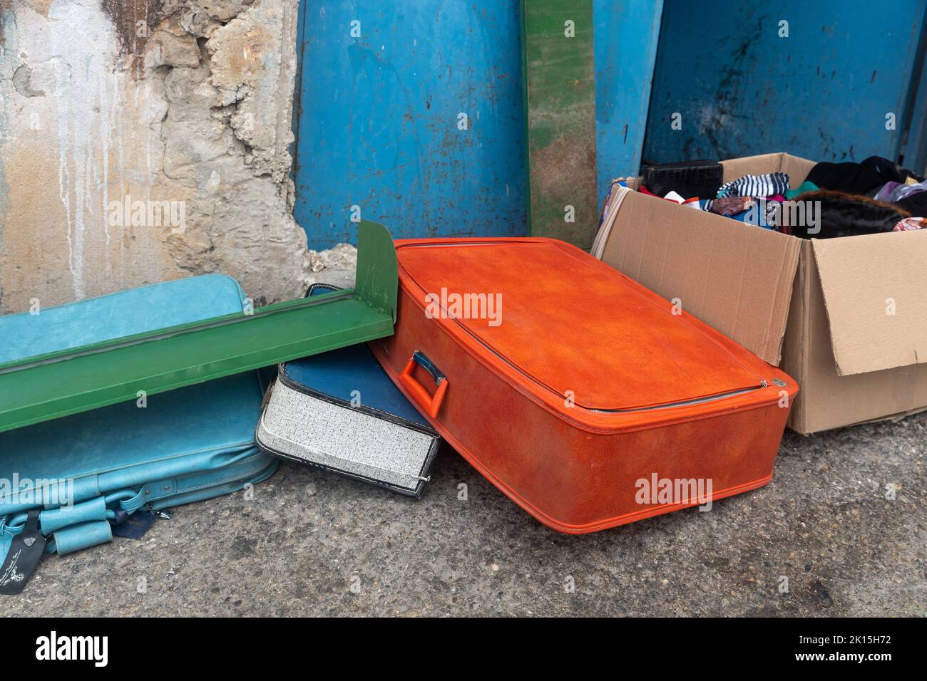 Old red discarded suitcase in the garbage Stock Photo