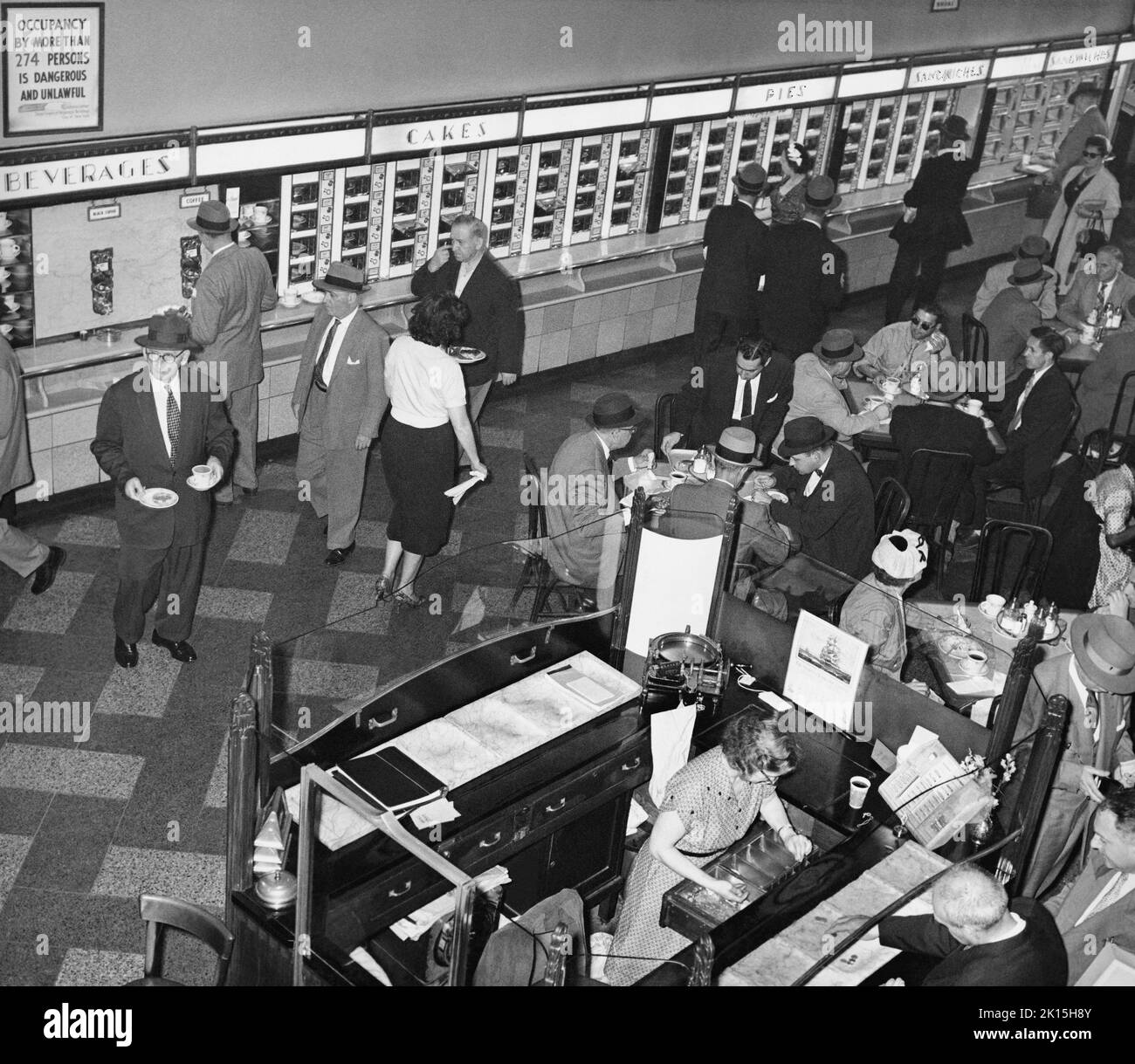 Horn & Hardart Automat Cafeteria on Avenue of the Americas at West 45th St., New York City, 1959. Horn & Hardart opened the first food service automat in New York City at Times Square on July 2, 1912. They took the concept from a successful German version. Their slogan was 'Less Work for Mother.' By the mid 20th century, there were over 50 Horn & Hardart restaurants in New York, serving 350,000 customers a day. In the 1960s, fast food franchises grew popular, and the automats began to close. Stock Photo