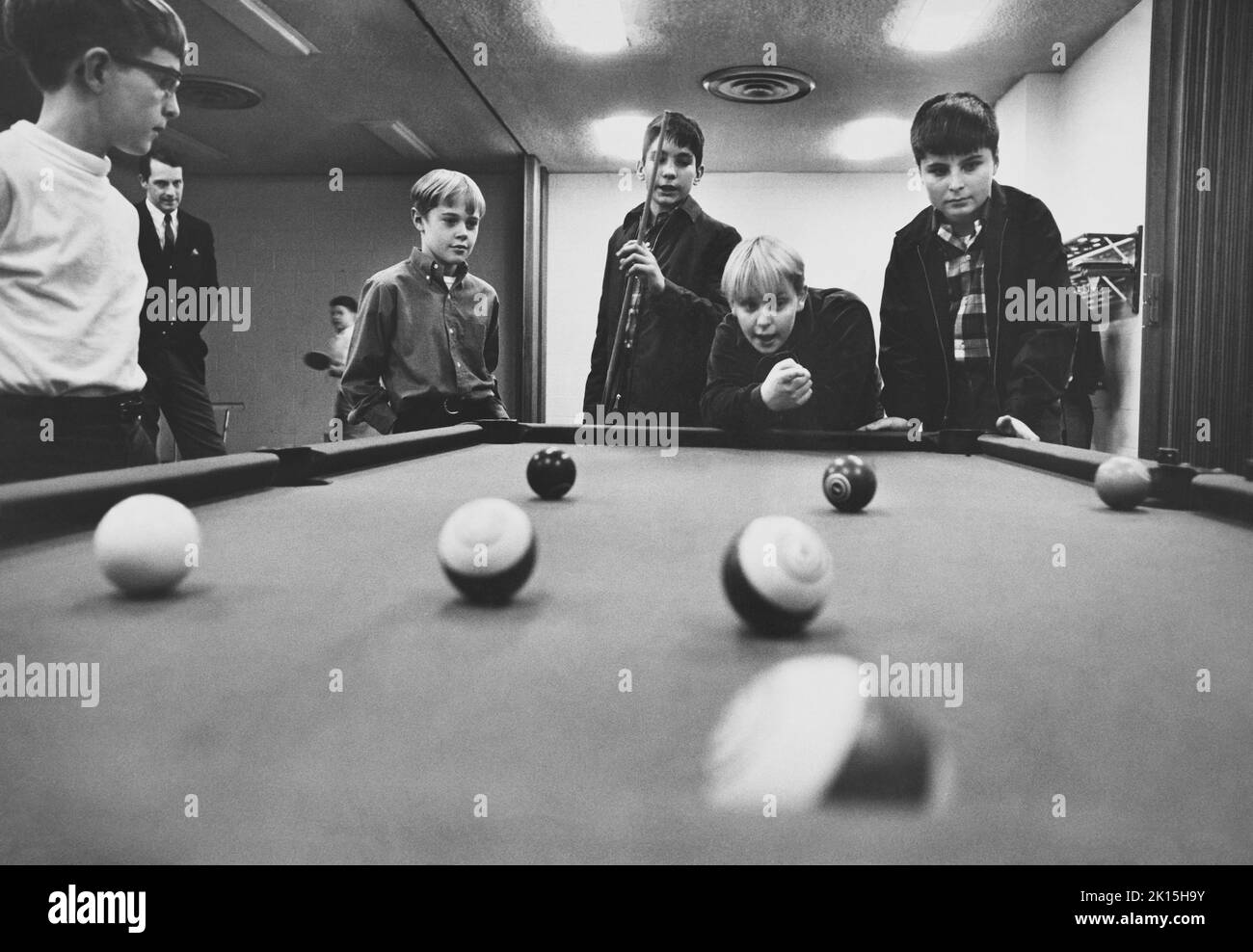 A group of boys play pool at a church recreation center in Atlanta, Georgia while an adult supervisor looks on. Pool, also more formally known as pocket billiards (mostly in North America) or pool billiards (mostly in Europe and Australia), is the family of cue sports and games played on a pool table having six receptacles called pockets along the rails, into which balls are deposited as the main goal of play. Popular versions include eight-ball and nine-ball. An obsolete term for pool is six-pocket. 1968, Stock Photo