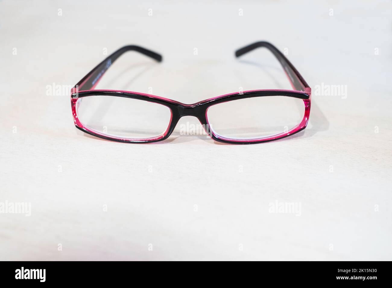 Pair of purple women's single vision reading glasses, or spectacles lying on a white background. Stock Photo