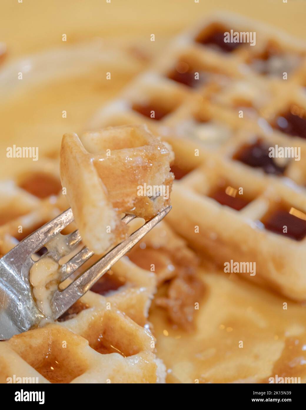 Homemade waffles smothered in maple syrup for breakfast. Yellow plate. USA. Stock Photo