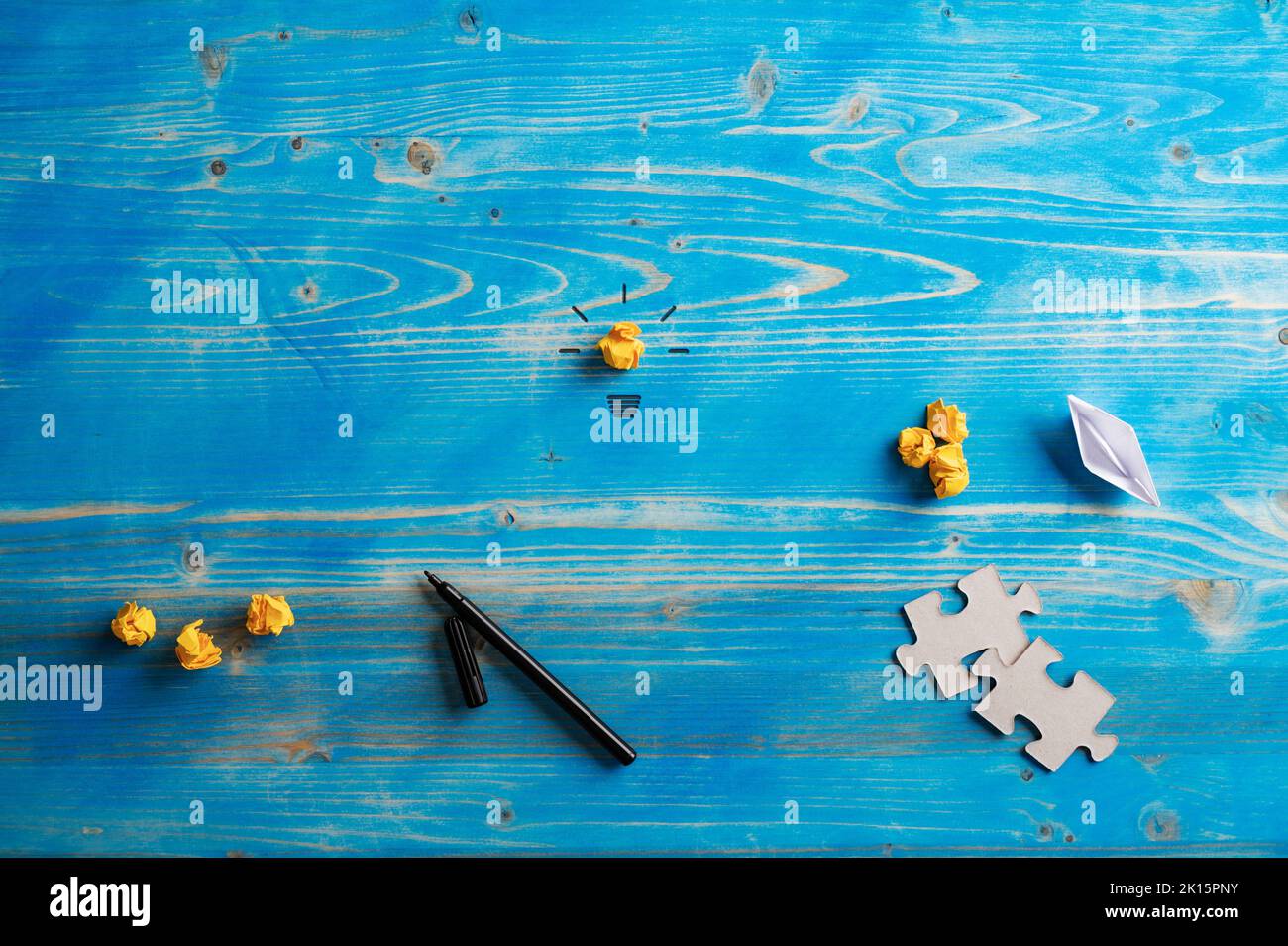 Conceptual image of brainstorming and idea - light bulb, puzzle pieces, smashed papers and black marker placed on blue wooden background with copy spa Stock Photo