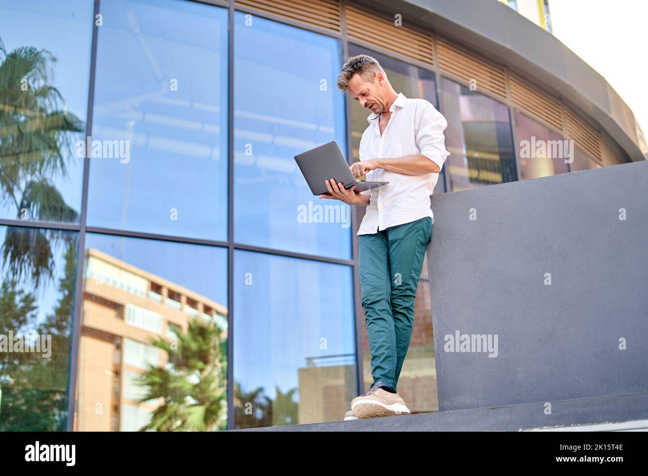 From below middle aged male manager leaning on border and browsing ...