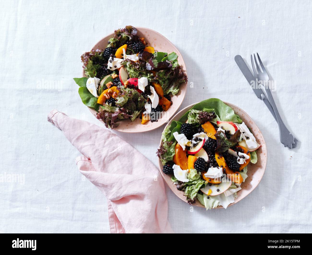 Top view with two plates of salad with roasted squash, berries and goat cheese. Vegetarian festive dinner. Stock Photo