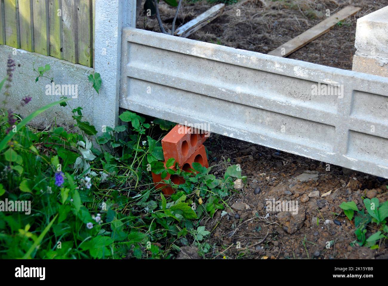 Temporary placement of a concrete gravel board during construction of  a fence Stock Photo