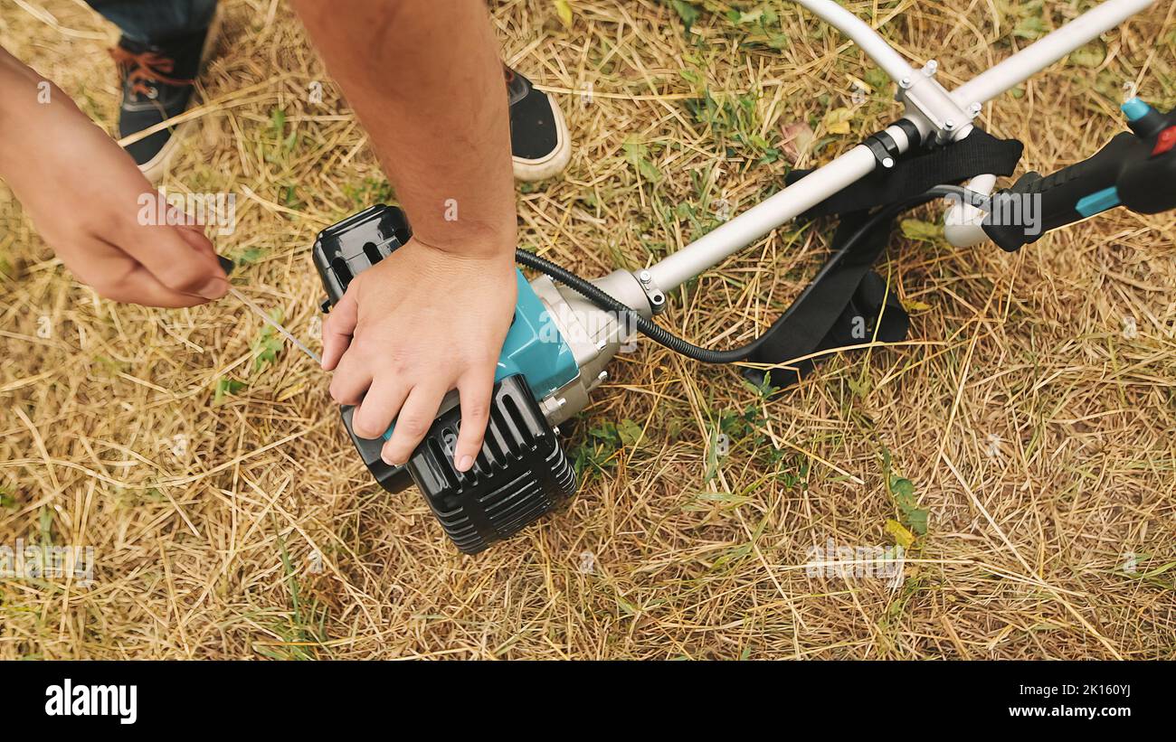 Gardener man hand starting gas lawn trimmer. Hands of a professional