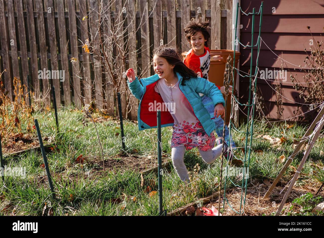 Two happy children play in sunshine in backyard garden Stock Photo