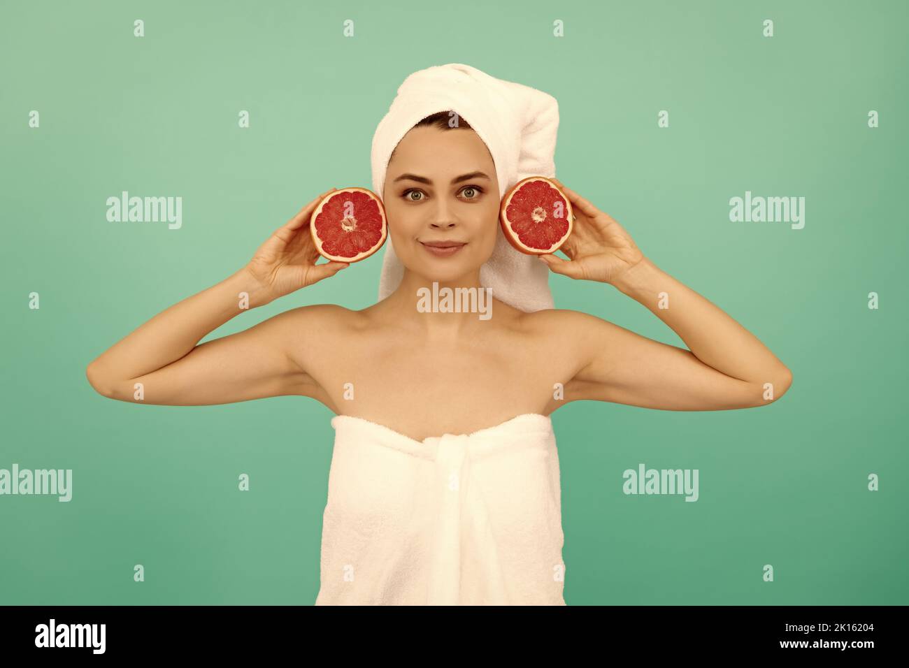 young girl in towel after shower with fruit on blue background Stock