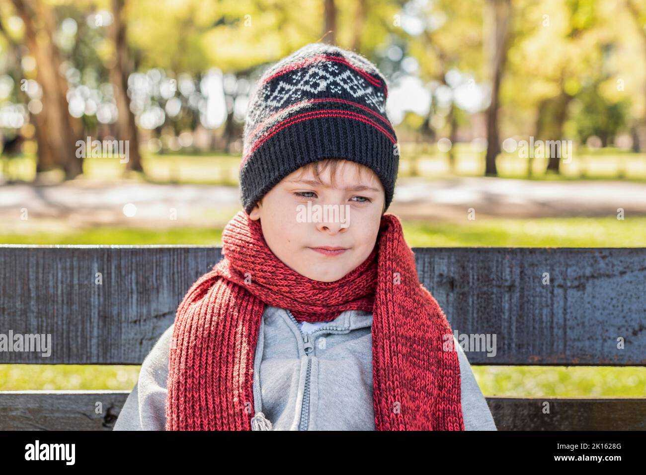 Thoughtful kid wearing a woolen hat and scarf in the Park Stock Photo
