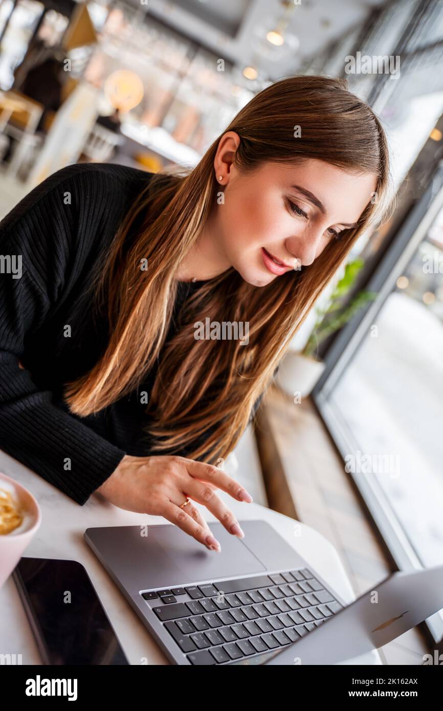 young girl at the window sitting at a laptop Stock Photo