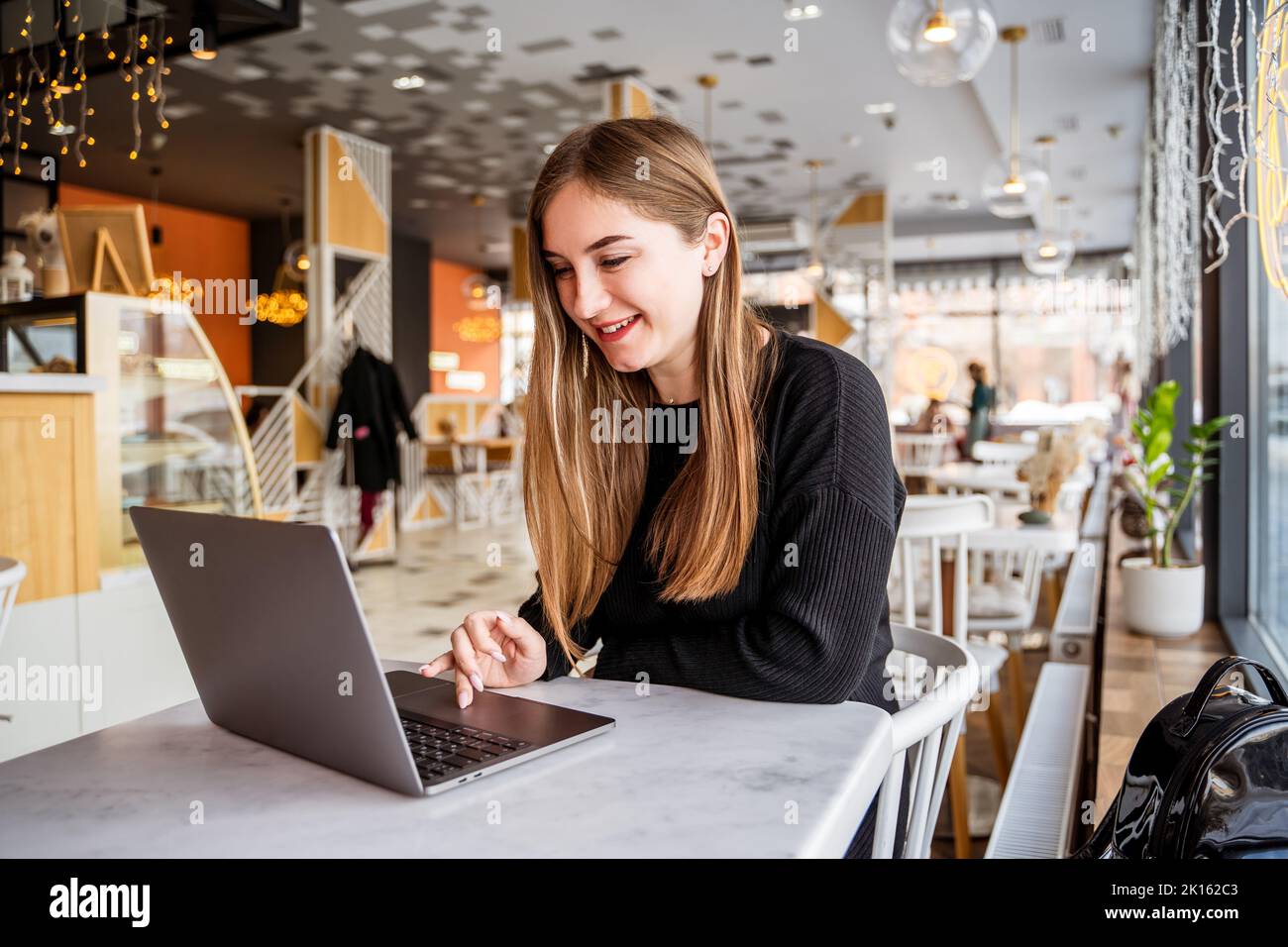 young girl in a cafe sitting at a laptop Stock Photo