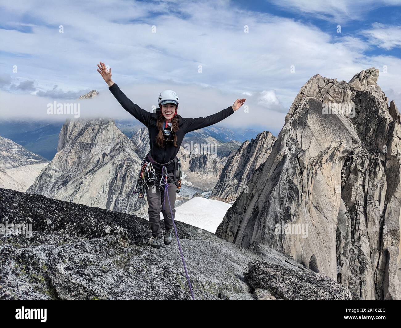 Female Climber Smiling on Summit of Rock Spire Stock Photo
