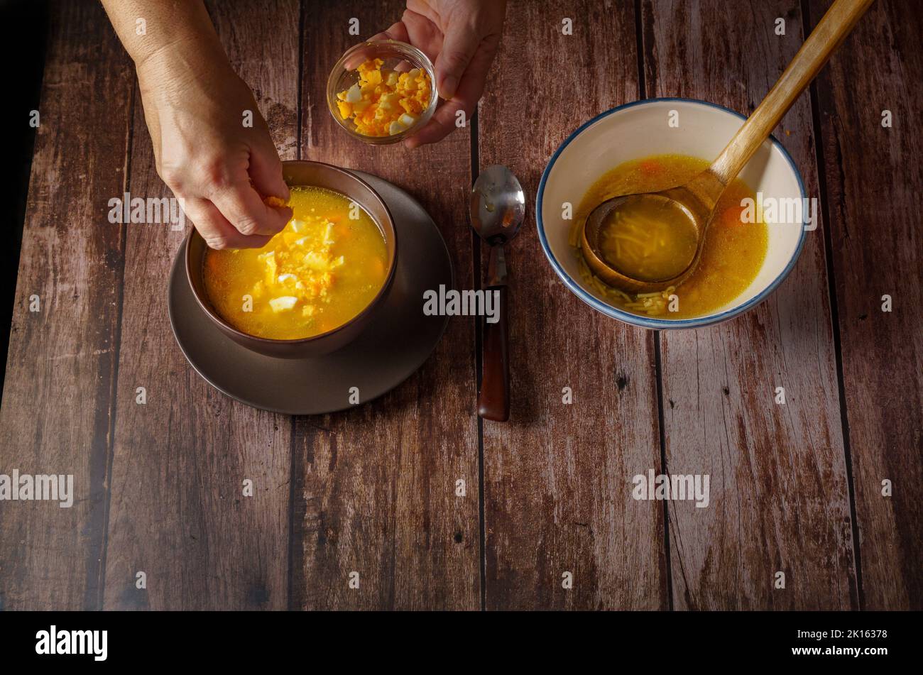 woman pouring hardboiled egg into a chicken noodle soup Stock Photo Alamy