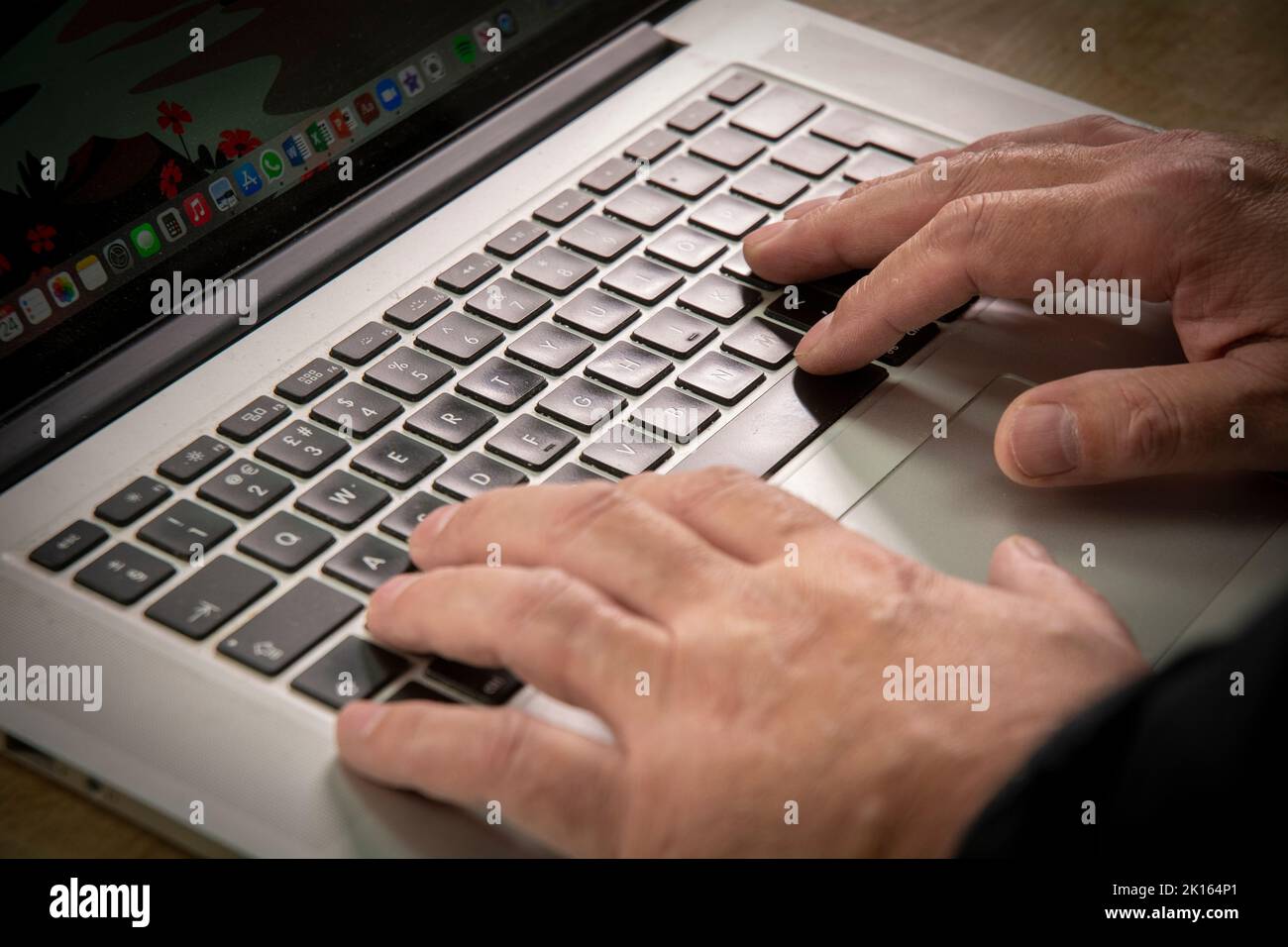 a male hand /  fingers typing on a computer laptop keyboard, apple macbook laptop Stock Photo