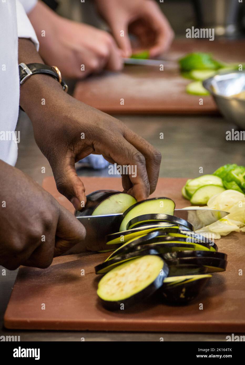 a chef and his student prepare and chop vegetables in the kitchen of the restaurant in a college training chefs Stock Photo