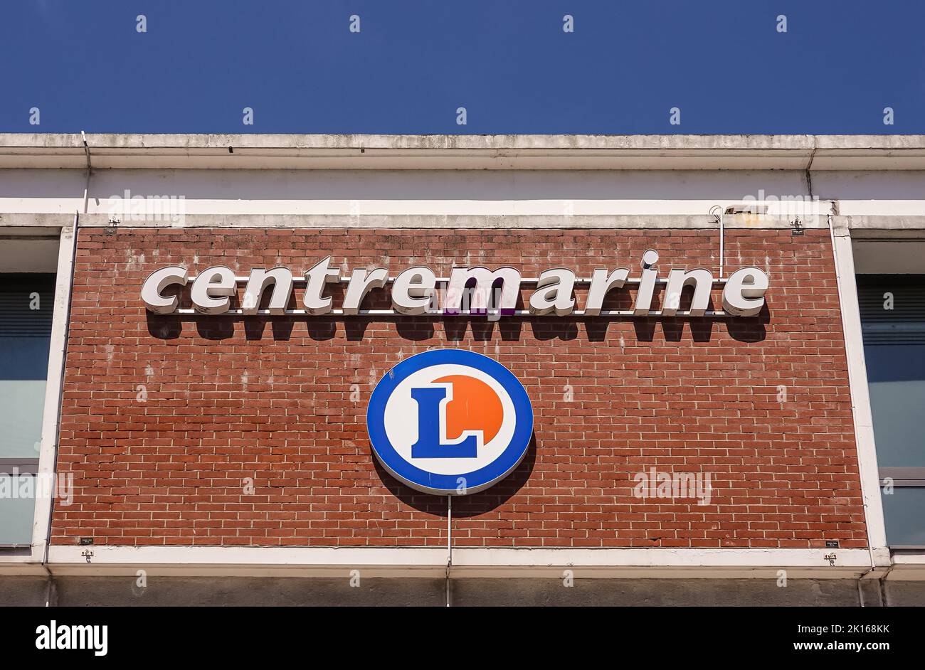 Europe, France, Dunkerque - July 9, 2022: Closeup of name sign on red brick wall of Centre Marine shopping mall under blue sky Stock Photo