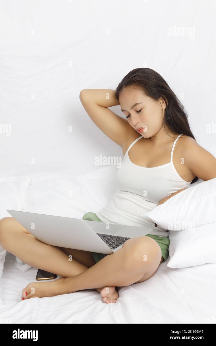 Asian woman working on a computer in bed isolated on white Stock Photo