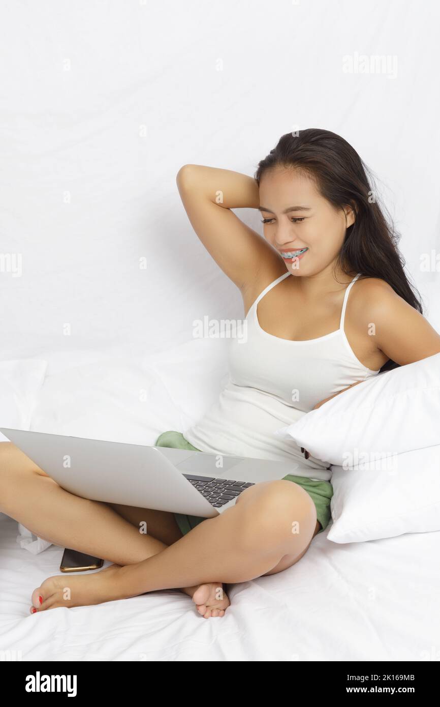 Asian woman working on a computer in bed isolated on white Stock Photo