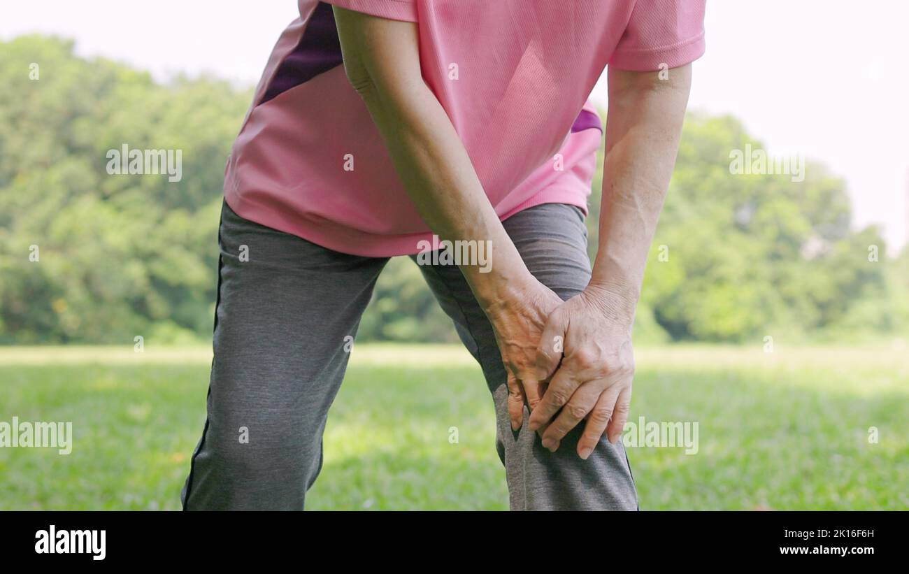 Senior woman feeling knee pain while exercising in the park Stock Photo