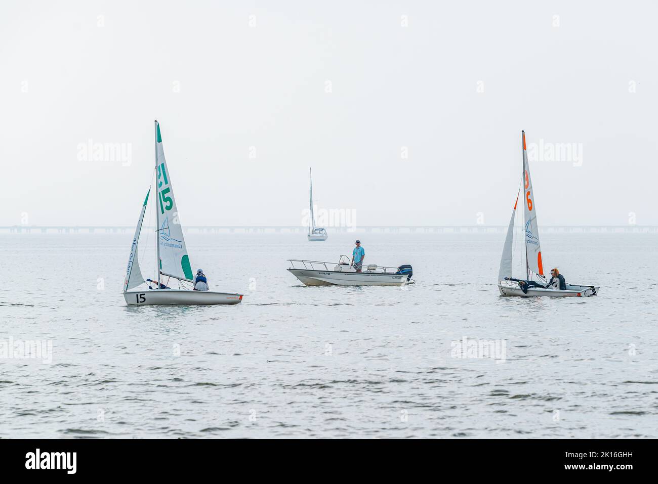 NEW ORLEANS, LA, USA - FEBRUARY 16, 2019: Small sailboat regatta on Lake Pontchartrain with two competitive boats, a monitor and fog in the background Stock Photo