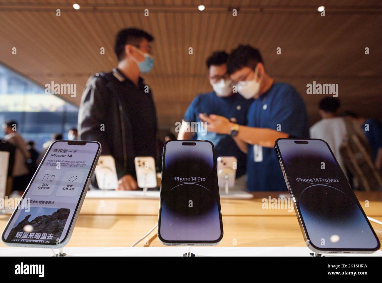 A customer talks to sales assistants in an Apple store as Apple Inc's new iPhone 14 models go on sale in Beijing, China, September 16, 2022. REUTERS/Thomas Peter Stock Photo