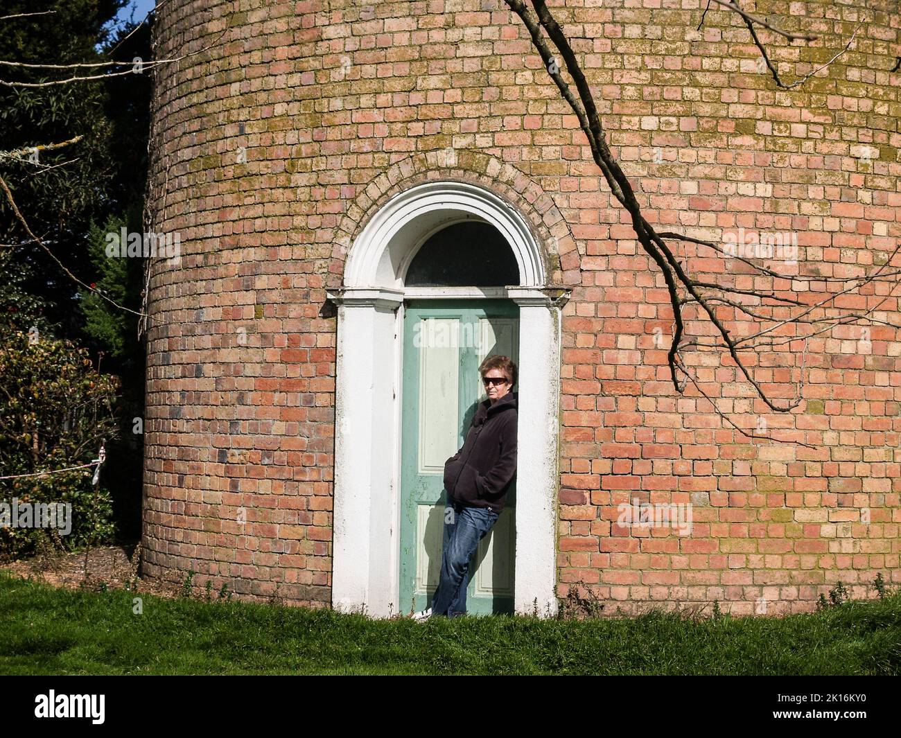 Cambridge-New Zealand- September 9 2008; Woman casually sheltering in doorway of old water-tower Stock Photo