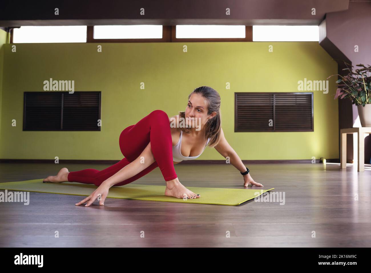 Woman practicing yoga, doing Uttan Prishthasana exercise, lizard pose, exercising in studio on mat, healthy lifestyle concept Stock Photo